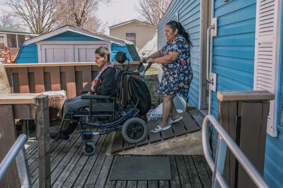 Maria Davila Hererra pushes her son, Christian Davila Reconco, 20, who was born with physical and developmental disabilities, down a ramp April 12 at their home in Iowa City to go to a bus stop. (Geoff Stellfox/The Gazette))