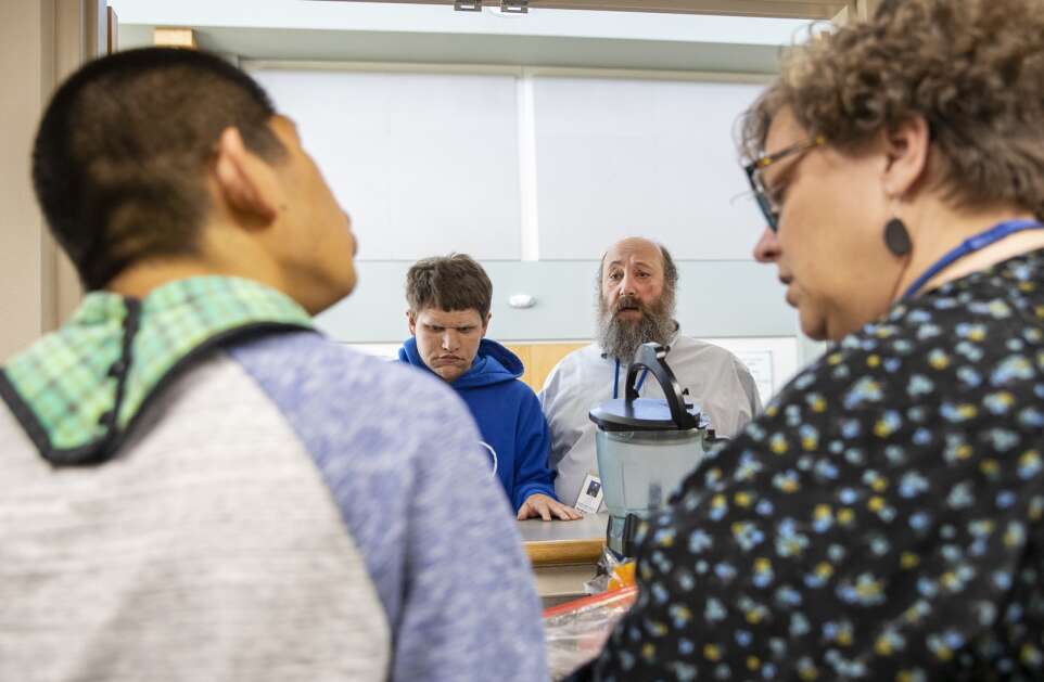 Paraeducator Diane Stoddard (right) sits with a student in the Clear  Creek Amana school district’s transition program during lunch Friday, with teacher Thomas Braverman and student Sam Graber in the background. (Savannah Blake/The Gazette)