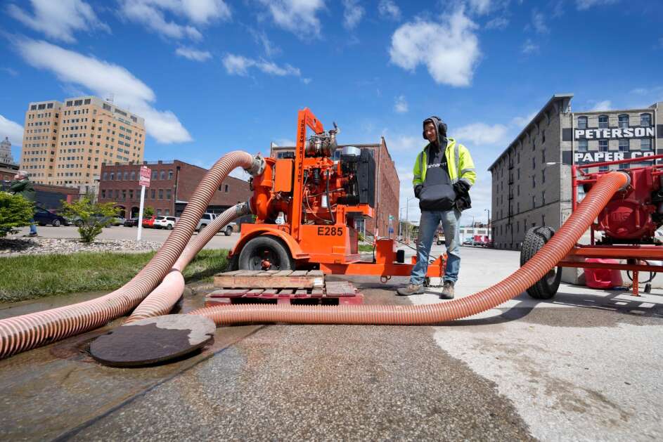 Davenport city worker Dylan Estlund monitors pumps Monday near a sand-filled flood barrier in the city’s downtown. (AP Photo/Charlie Neibergall)