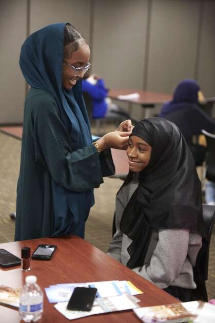 Lamar Mohammad, left, adjusts the hijab of Omnia Ali, both 15 of Iowa City, as members of the Mariam Girls’ Club prepare for an upcoming annual World Hijab Day event at the Coralville Public Library on Saturday. The club is partnering for the second year with the library to host a public World Hijab Day event on Feb. 1. The public is invited to learn about the hijab and women in Islam. The event offers the opportunity to chat with Muslims along with snacks, games, educational material on women in Islam and females attending the event will be able to try on and keep a hijab. (Cliff Jette/Freelance)