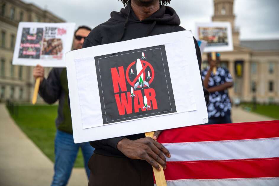 Organizers pass out signs for attendees during a rally to bring awareness to the ongoing Sudan civil war on Saturday, April 29, 2023, at the Pentacrest in Iowa City, Iowa. (Geoff Stellfox/The Gazette)