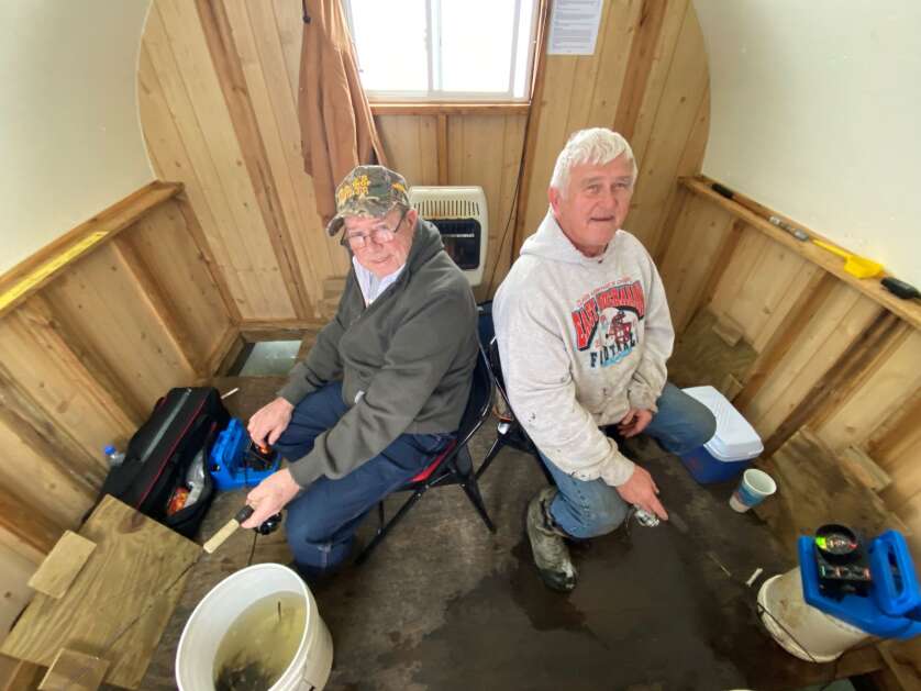 Dean Paragari (left) of Monty and Mike Stafford of Winthrop jig for walleye and hawk on Jan. 25 in the warm comfort of their Lake of the Woods ice fishing shack.  (Orlan Love/Reporter) 