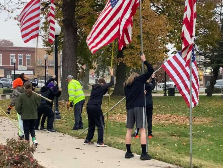 Volunteers, city staff and students put up flags in Fairfield’s Central Park