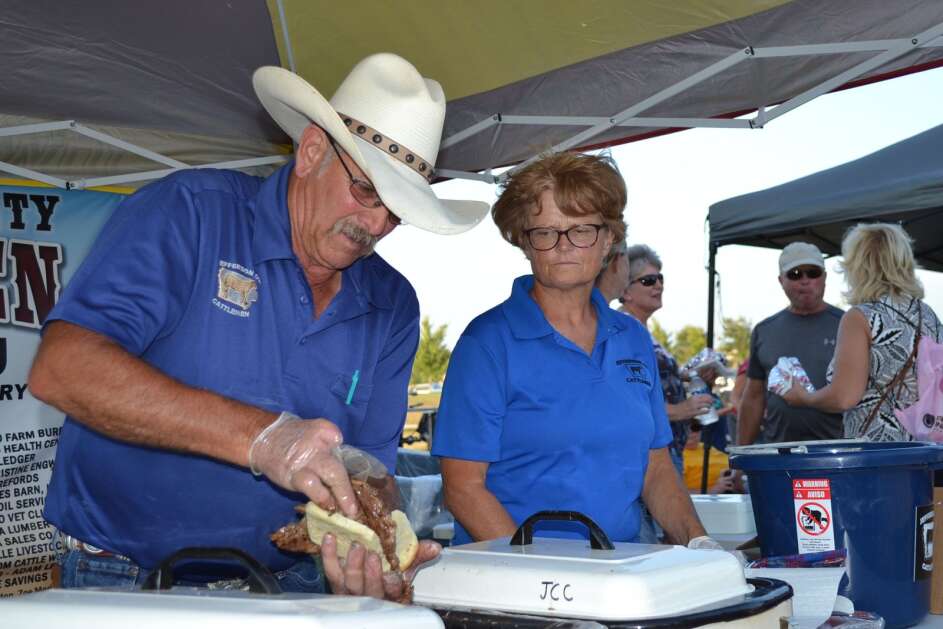 Rick Coffman, left, and Zoe Moritz serve ribeyes and hamburgers at the Jefferson County Cattlemen’s booth Friday during the Barnyard Bash at Maasdam Barns in Fairfield. (Andy Hallman/The Union)