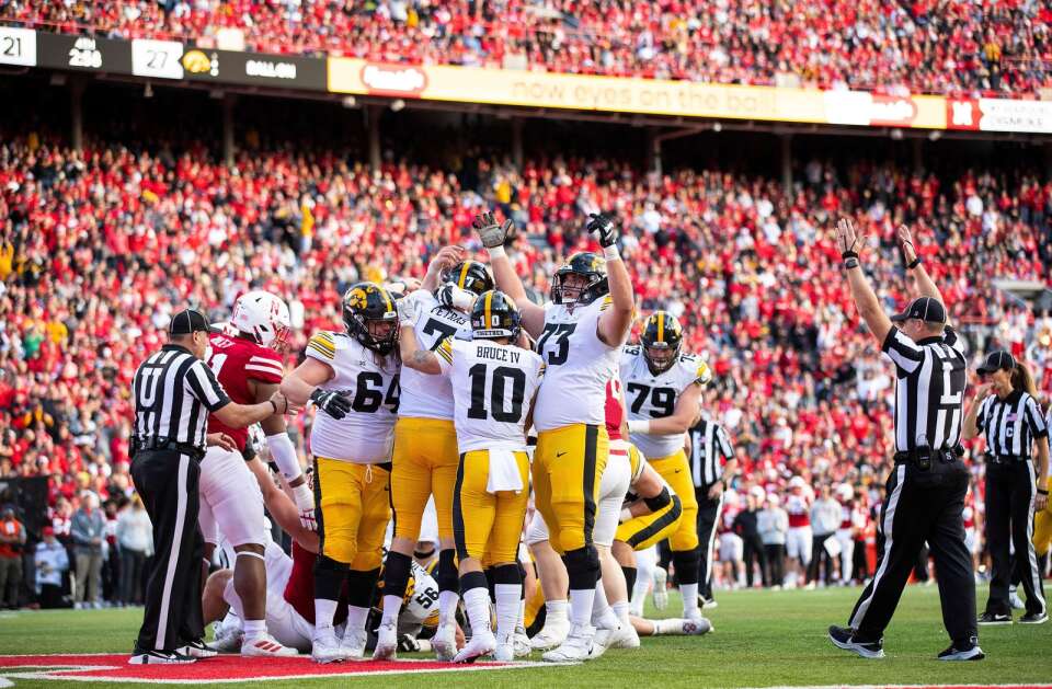 Iowa's Kyler Schott (64), Spencer Petras (7), Arland Bruce IV (10) and Cody Ince (73) celebrate Petras' touchdown against Nebraska during the second half of an NCAA college football game Friday, Nov. 26, 2021, at Memorial Stadium in Lincoln, Neb. Iowa defeated Nebraska 28-21. (AP Photo/Rebecca S. Gratz)